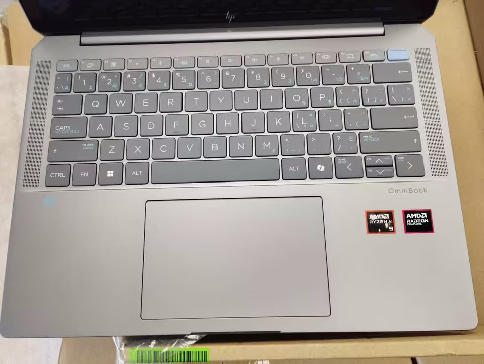 HP OmniBook Ultra laptop closeup showing backlit keyboard, wide precision trackpad, dual speaker grills, and AMD Ryzen AI 9 with Radeon Graphics badges